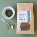 Rooibos tea packaging with a bowl of Rooibos tea leaves and a spoon on a green background
