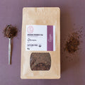 Rooibos Tea package with a spoonful of Rooibos tea and Cacao husks  on a purple background