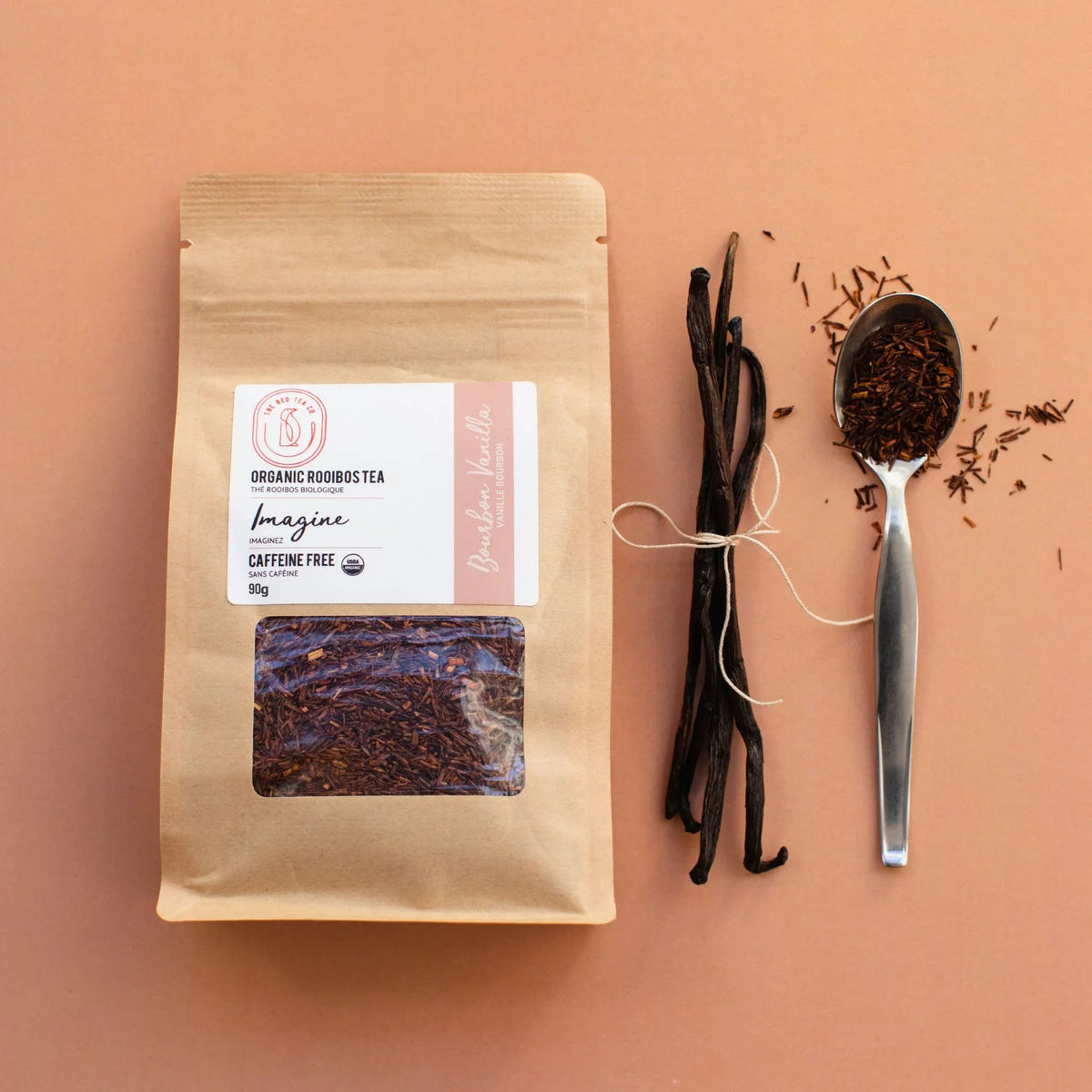 Organic Rooibos tea package with visible loose leaf tea, tied vanilla pods, and a spoonful of tea on tan background